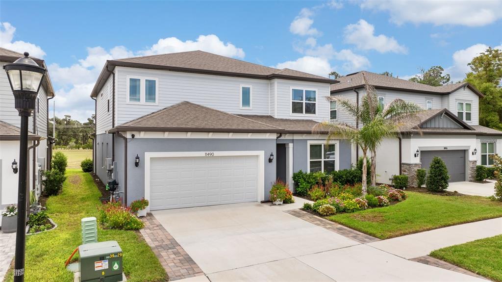 A two-story suburban house with a gray exterior, a two-car garage, and a paved driveway — 11490 CALUSA TRAILS WAY, RIVERVIEW, FL