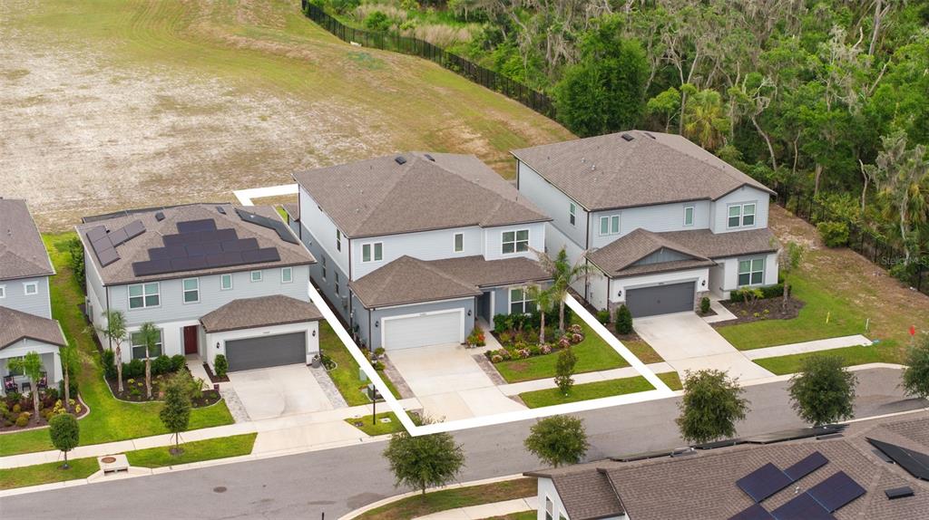 An aerial view shows three suburban houses with gray siding and driveways along a street — 11490 CALUSA TRAILS WAY, RIVERVIEW, FL