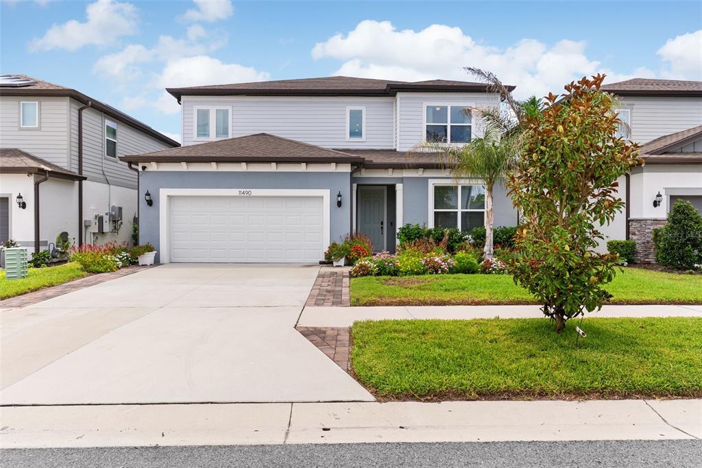 A two-story suburban house features a gray exterior, a two-car garage, and a landscaped yard — 11490 CALUSA TRAILS WAY, RIVERVIEW, FL
