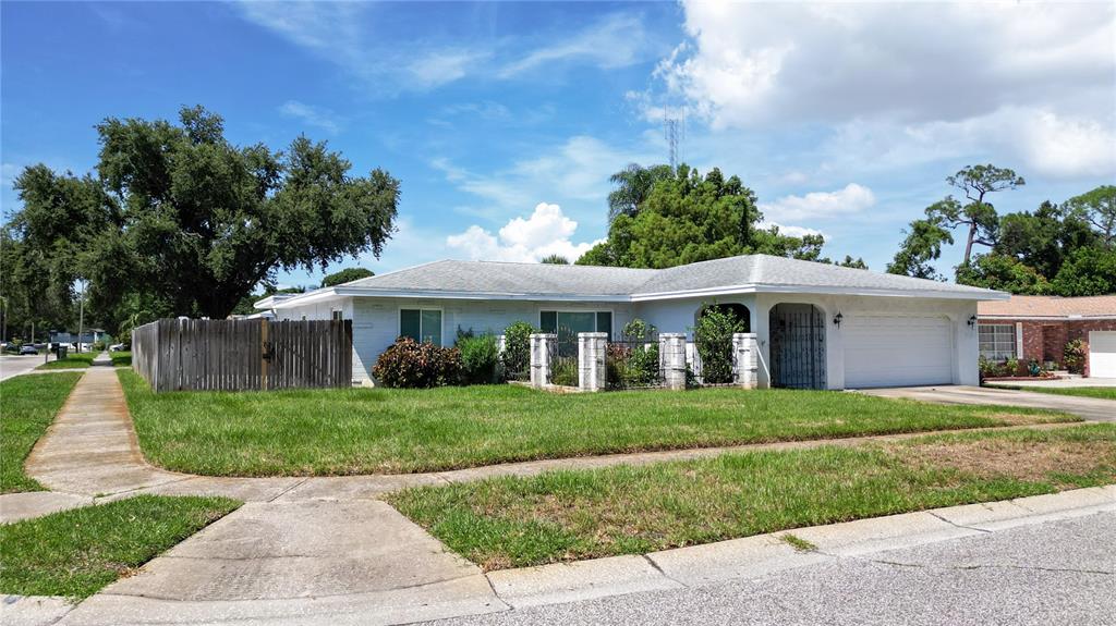 A single-story white house with a two-car garage and a wooden fence — 11051 130TH AVENUE, LARGO, FL
