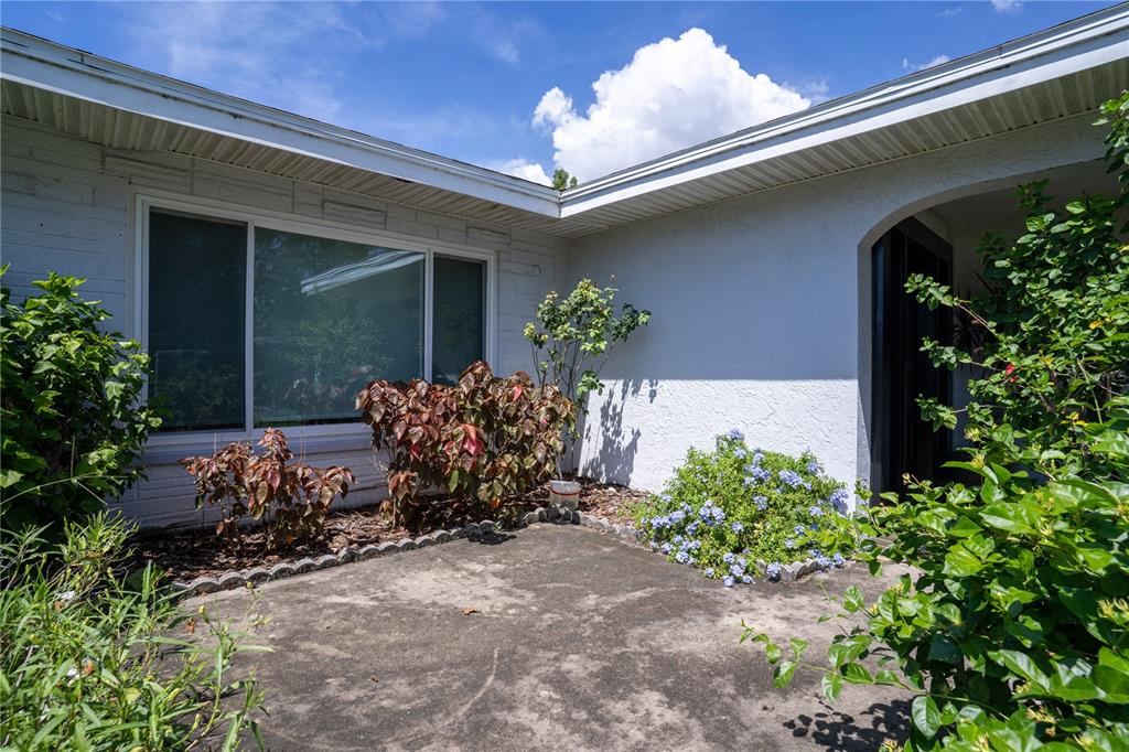 A concrete patio sits in front of a white house with a large window — 11051 130TH AVENUE, LARGO, FL