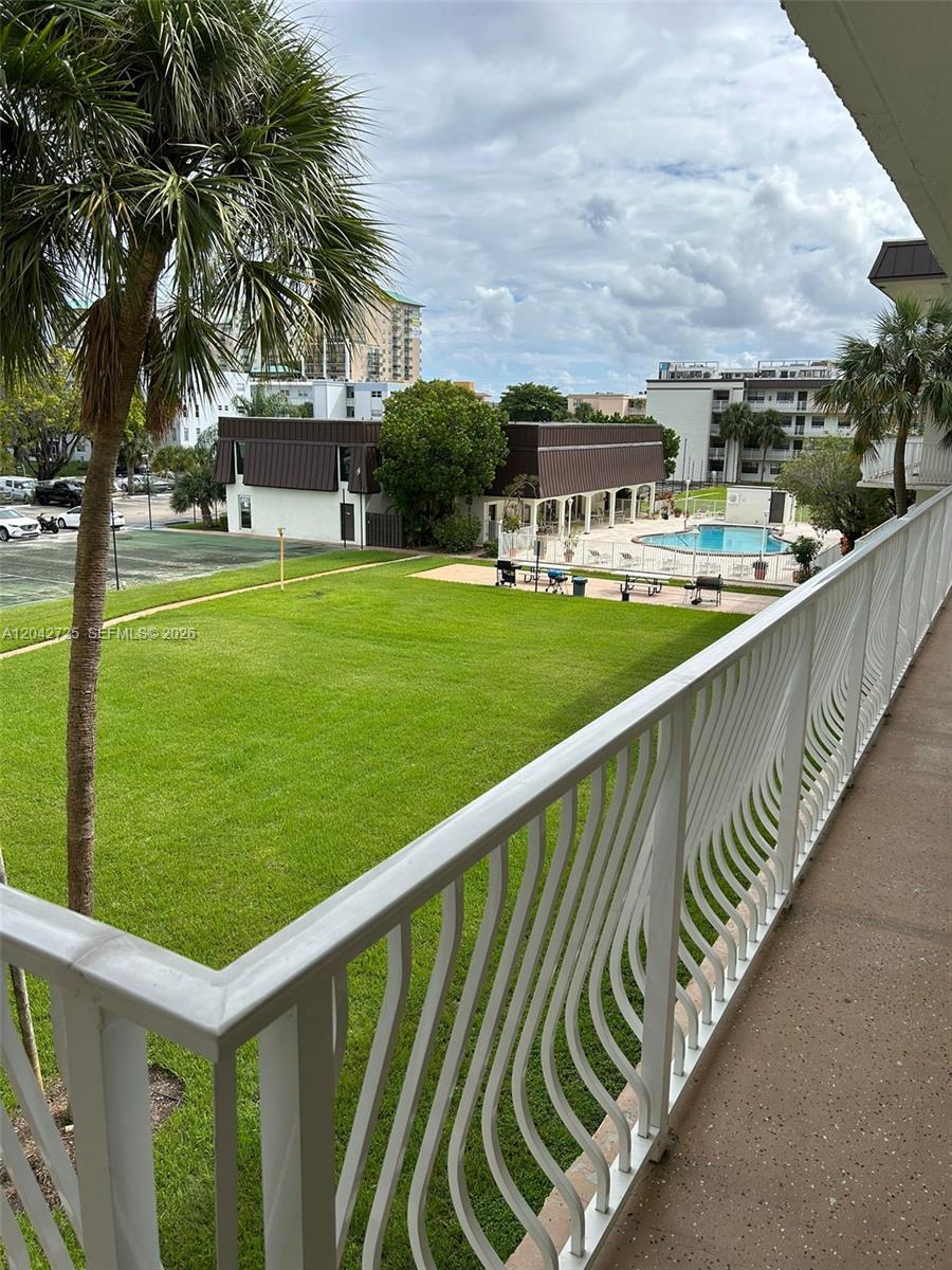A view from a balcony overlooking a grassy lawn, a swimming pool, and buildings — 500 NE 2nd St # 310, Dania Beach FL 33004, DANIA BEACH, FL