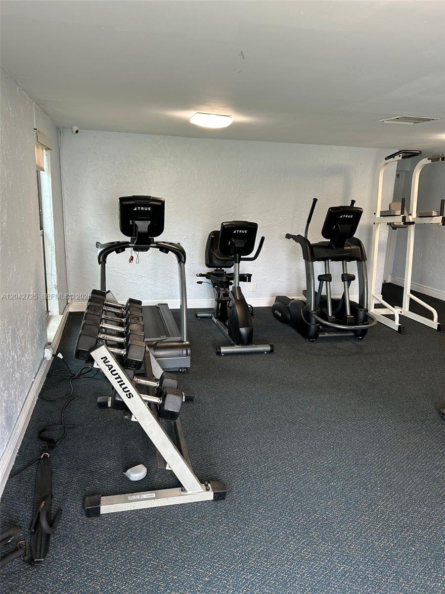 A home gym features a treadmill, stationary bike, elliptical, weight rack, and pull-up station — 500 NE 2nd St # 310, Dania Beach FL 33004, DANIA BEACH, FL