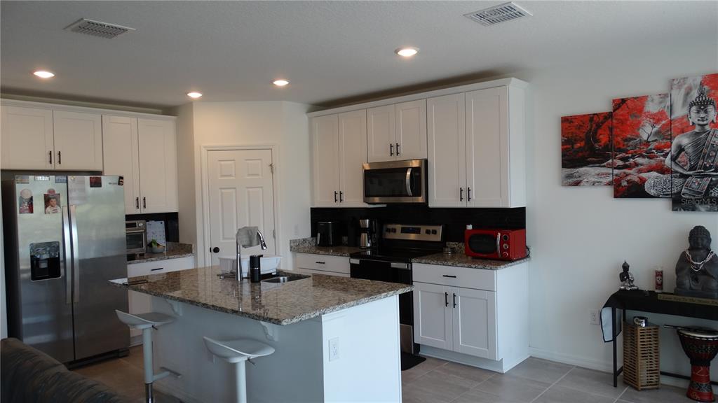 A kitchen features white cabinets, granite countertops, stainless steel appliances, and a central island — 3138 VICEROY COURT, KISSIMMEE, FL