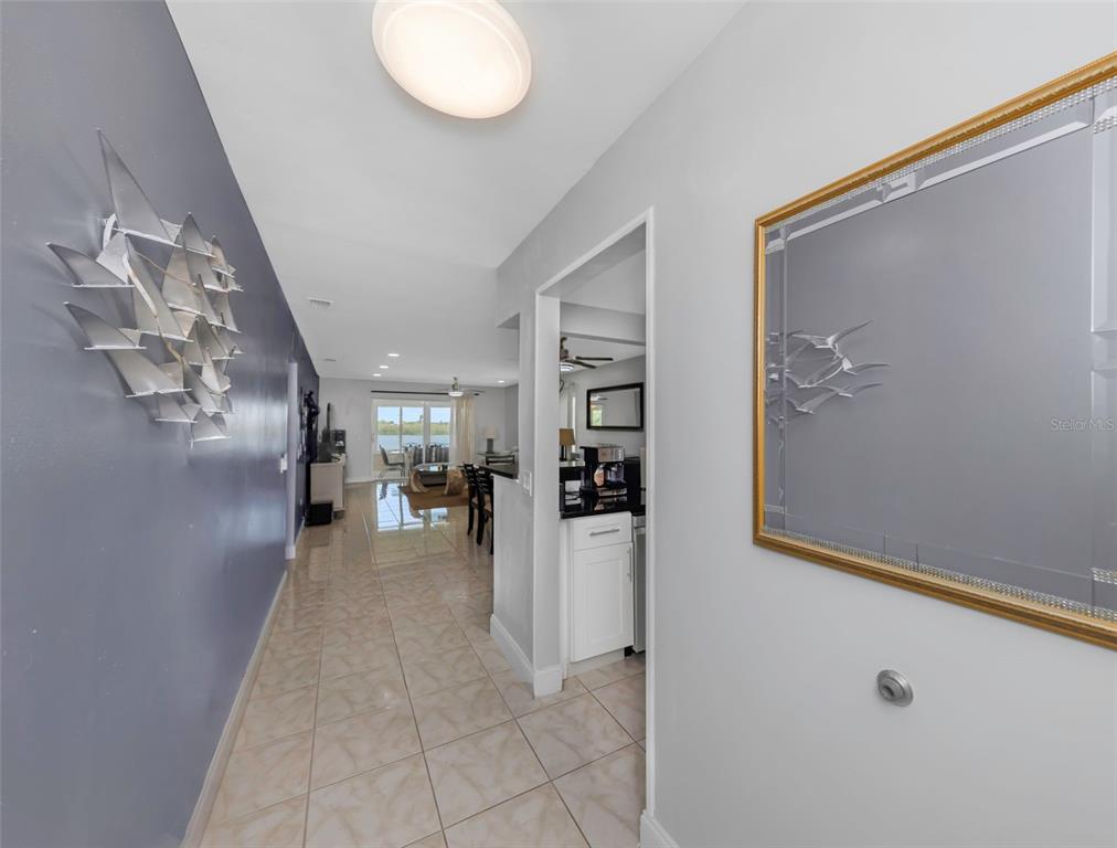 A hallway with tiled floors leads to an open living area with a water view — 1819 SHORE DRIVE S UNIT 318, SOUTH PASADENA, FL