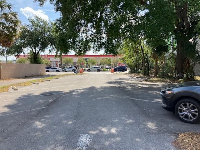 A paved parking lot leads toward a gas station under a canopy of trees — 103 S HOWARD AVENUE, TAMPA, FL