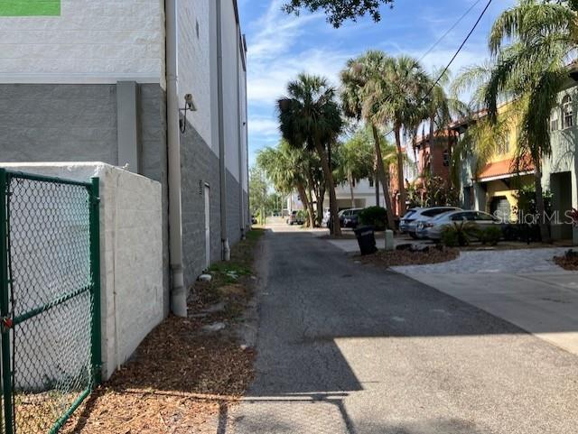 An alleyway runs between a white building and a row of palm trees and houses — 103 S HOWARD AVENUE, TAMPA, FL