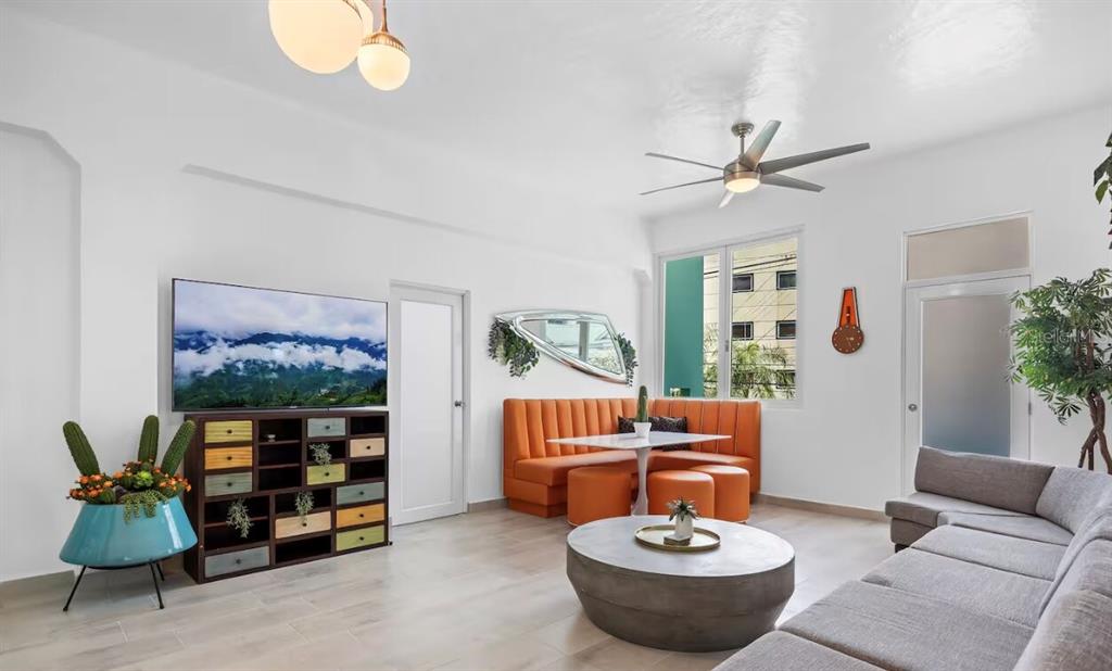 A living room features a grey sectional sofa, orange booth seating, and a colorful media console — 250 CALLE DEL PARQUEZ UNIT 2B, SAN JUAN, PR