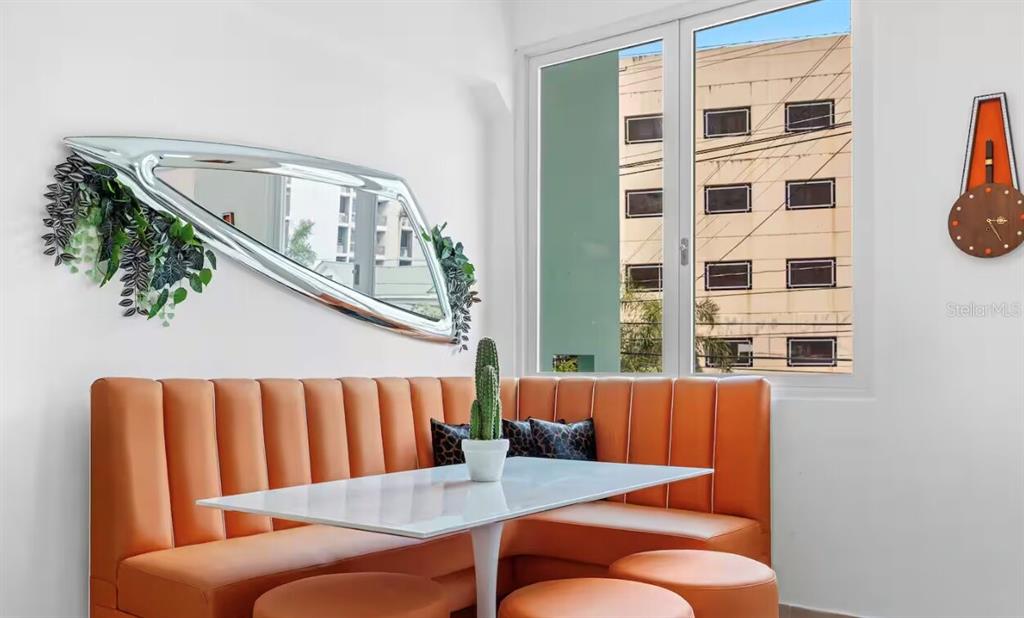 A dining nook features an orange banquette, a white table, and a modern wall mirror — 250 CALLE DEL PARQUEZ UNIT 2B, SAN JUAN, PR