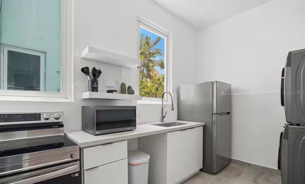 A modern kitchen features white cabinets, stainless steel appliances, a sink, and a window — 250 CALLE DEL PARQUEZ UNIT 2B, SAN JUAN, PR