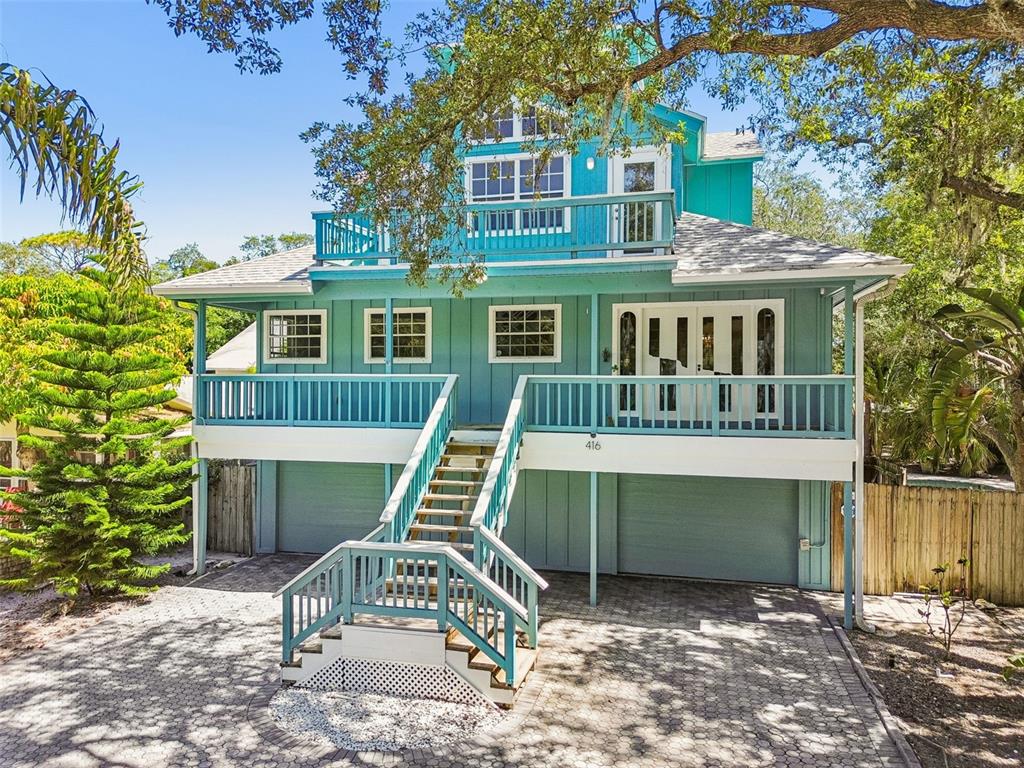 A teal two-story house with a raised deck, central staircase, and a paved driveway — 416 TENNESSEE AVENUE, CRYSTAL BEACH, FL