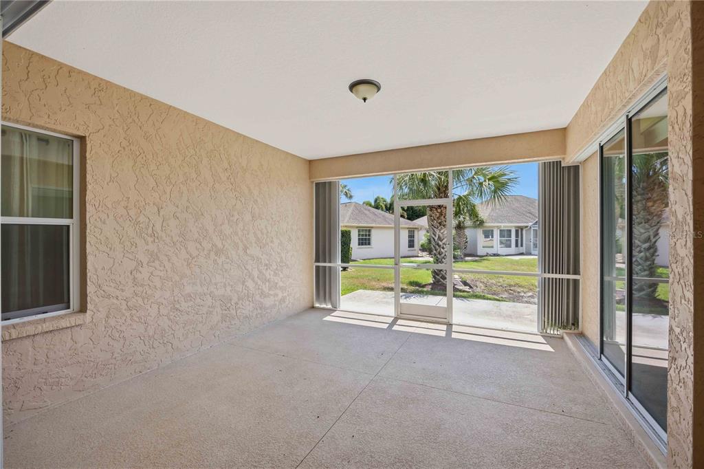 A screened-in patio with beige textured walls, concrete flooring, and a view of a backyard — 409 TOMOKA DRIVE, ENGLEWOOD, FL