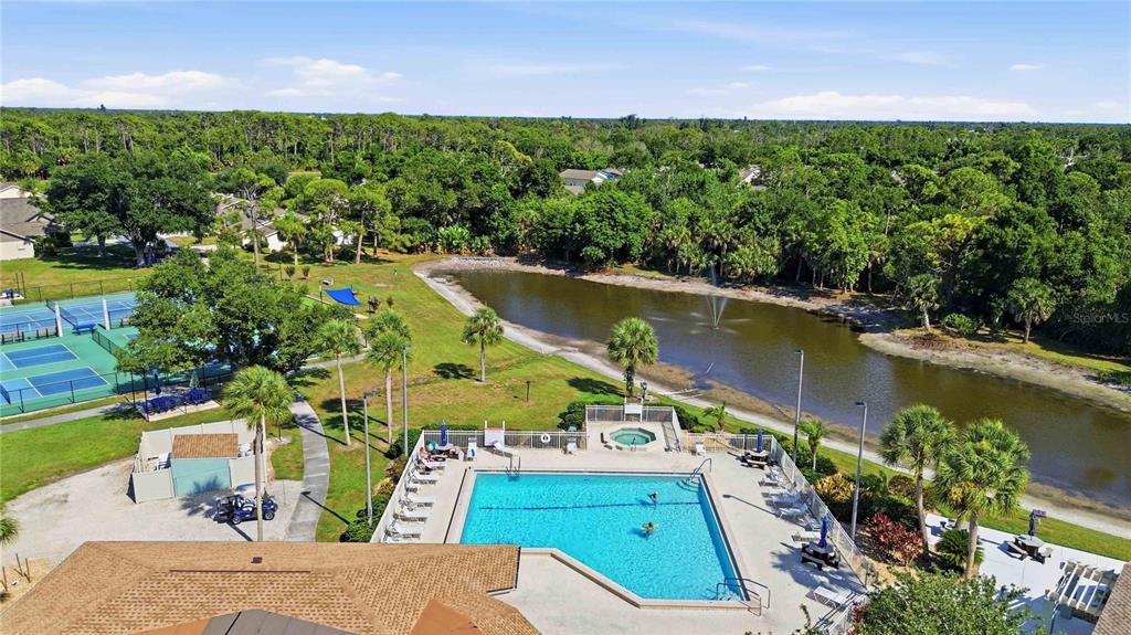 An aerial view shows a community swimming pool, hot tub, tennis courts, and a pond — 409 TOMOKA DRIVE, ENGLEWOOD, FL