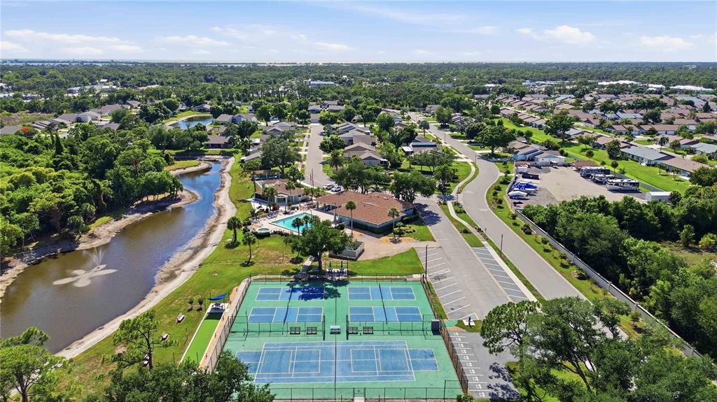 An aerial view shows a community tennis court, swimming pool, clubhouse, and a nearby pond — 409 TOMOKA DRIVE, ENGLEWOOD, FL