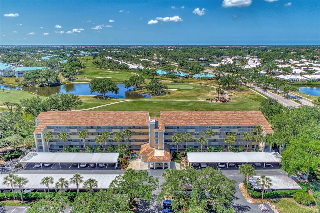 An aerial view shows a multi-story apartment building with covered parking lots and a golf course — 841 WEXFORD BOULEVARD UNIT 841, VENICE, FL