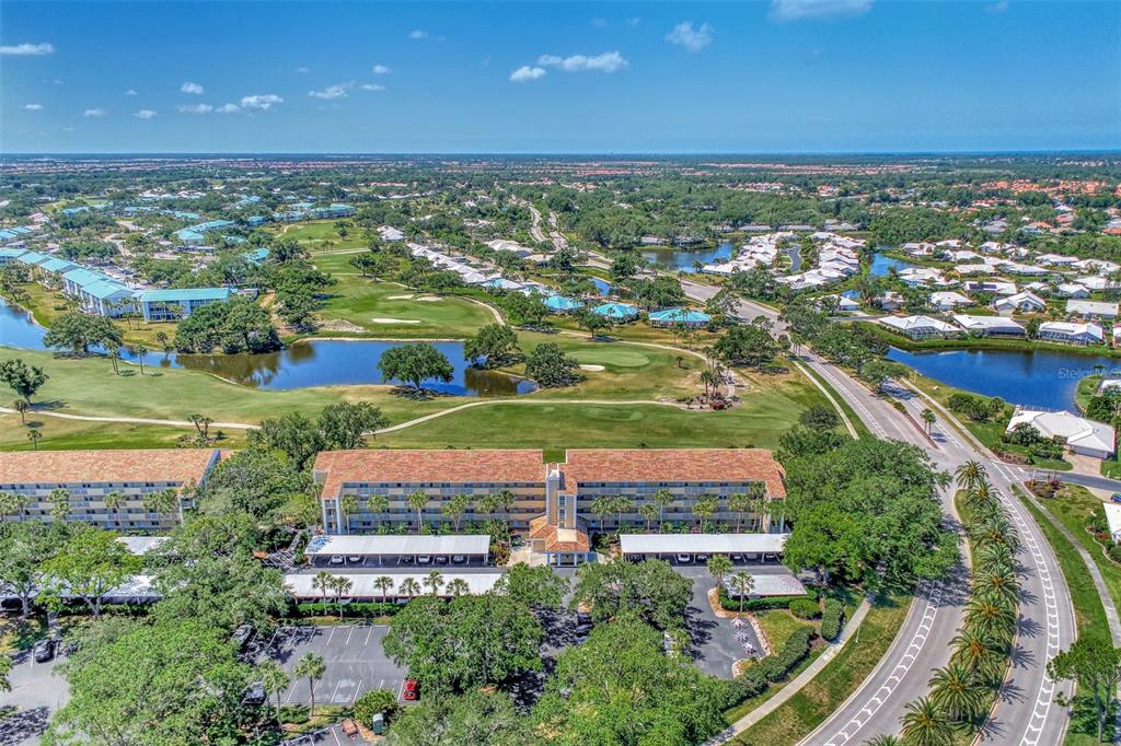 An aerial view shows a multi-story apartment building surrounded by a golf course and ponds — 841 WEXFORD BOULEVARD UNIT 841, VENICE, FL