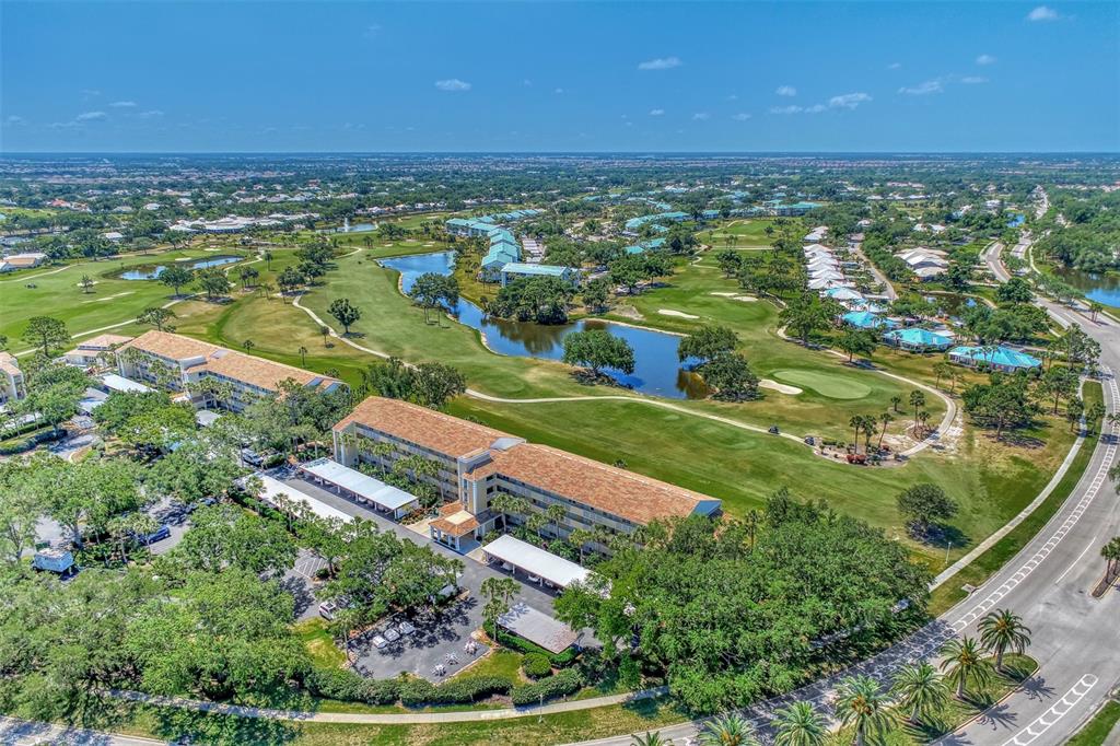 An aerial view shows a multi-story building situated next to a golf course and pond — 841 WEXFORD BOULEVARD UNIT 841, VENICE, FL