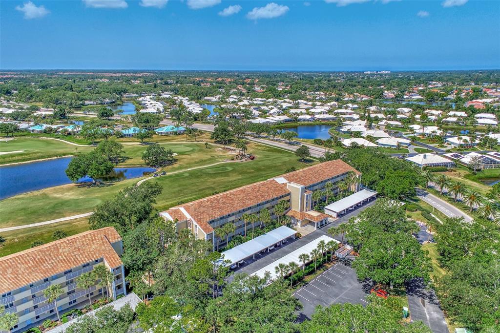 An aerial view shows two multi-story apartment buildings surrounded by trees, a golf course, and ponds — 841 WEXFORD BOULEVARD UNIT 841, VENICE, FL