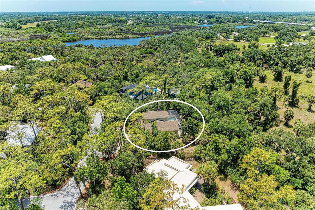 An aerial view shows a house with a pool surrounded by dense trees and vegetation — 5911 RIVER FOREST CIRCLE, BRADENTON, FL