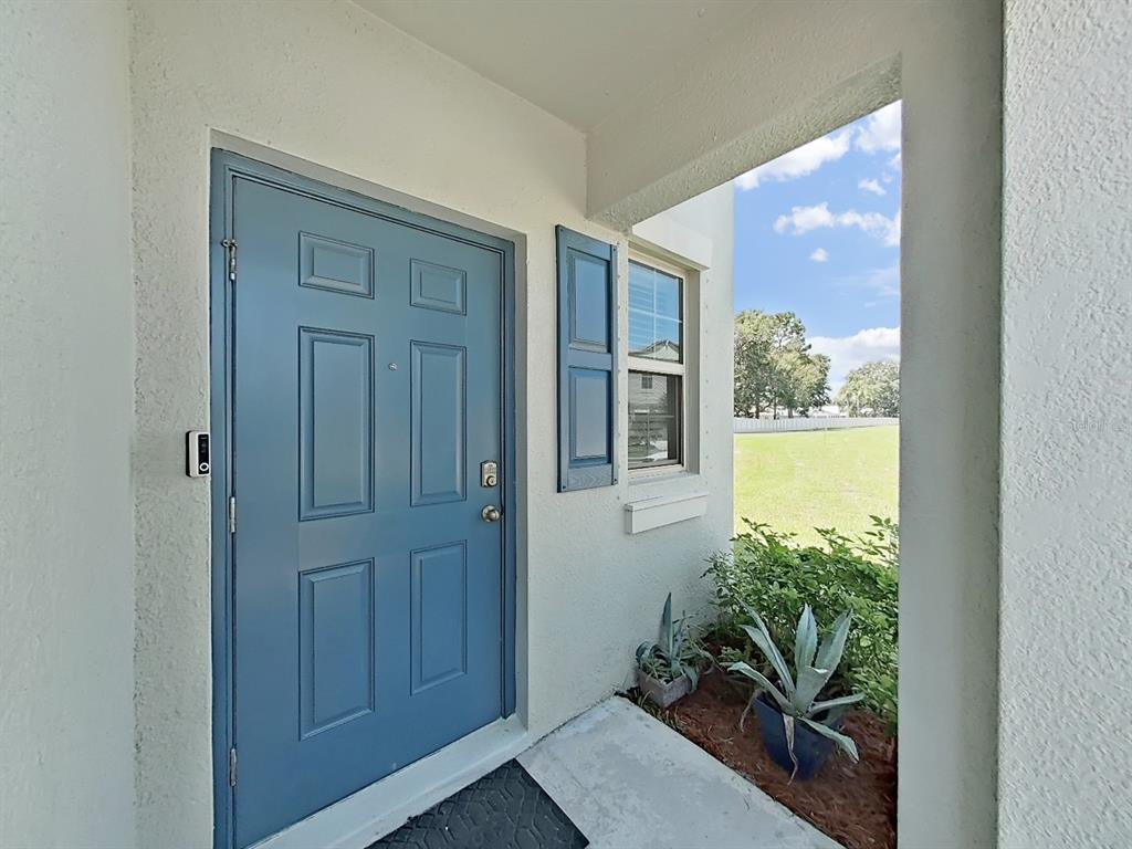 A blue front door with a window and shutters sits under a covered entryway — 13678 SEA BRIDGE DRIVE, HUDSON, FL