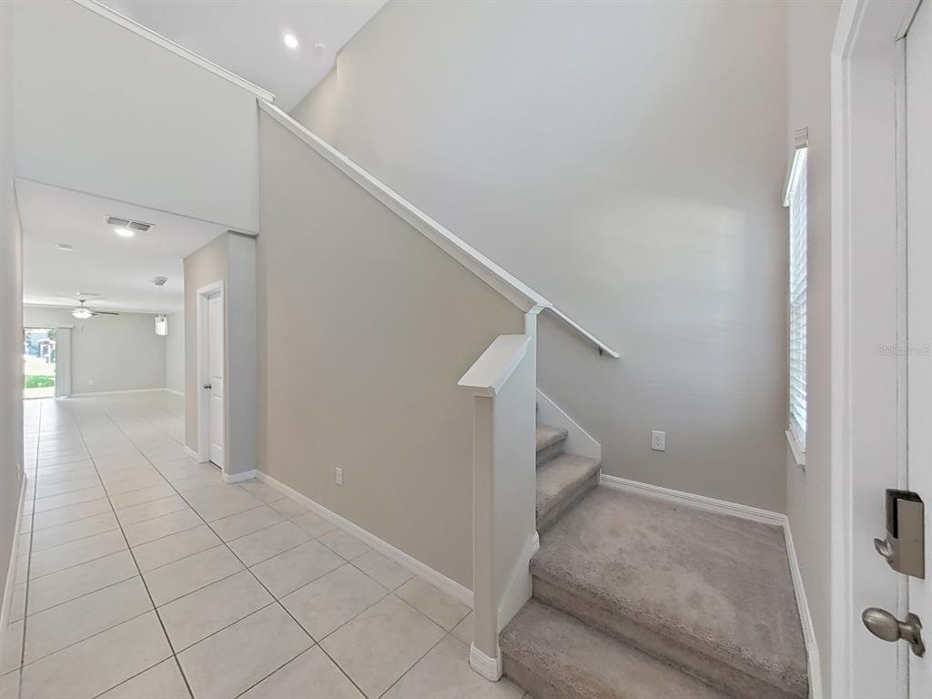 An entryway features a tiled floor, a carpeted staircase, and a view into the home — 13678 SEA BRIDGE DRIVE, HUDSON, FL