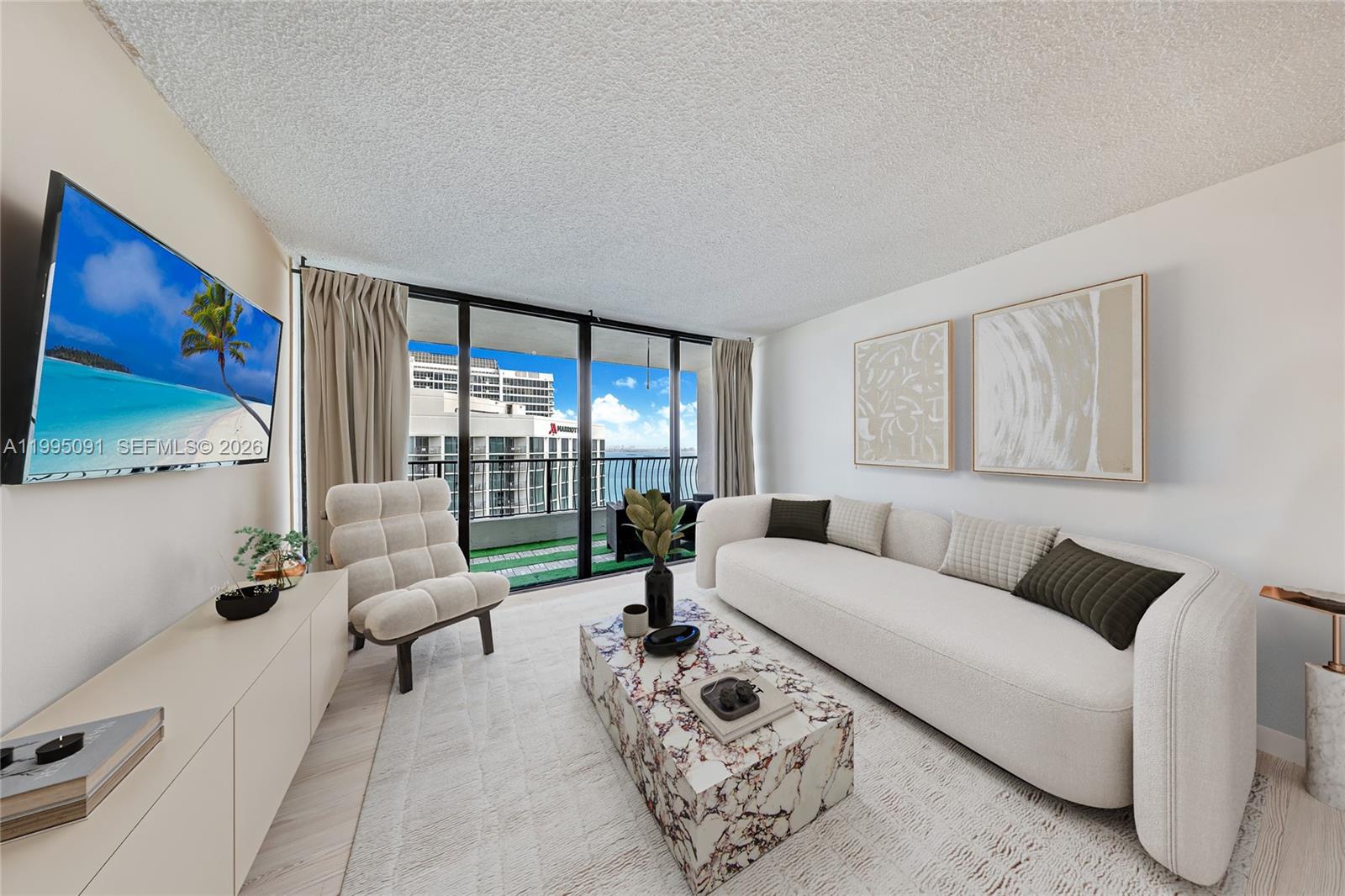 A living room features a white sofa, marble coffee table, accent chair, and balcony view — 555 NE 15th St # 33G, Miami FL 33132, MIAMI, FL