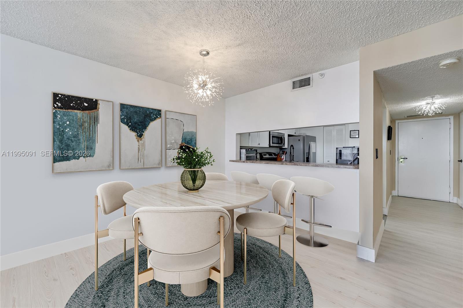 A dining area features a round table, upholstered chairs, a chandelier, and a kitchen pass-through — 555 NE 15th St # 33G, Miami FL 33132, MIAMI, FL