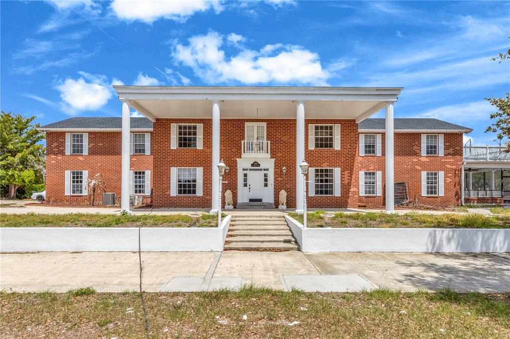 A two-story brick house features a large front porch supported by four white columns — 1585 S CARPENTER ROAD, TITUSVILLE, FL