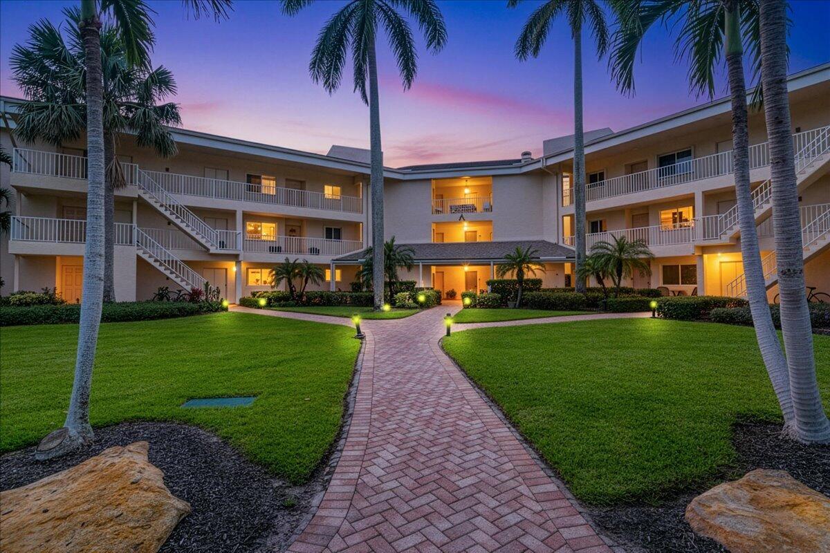 A brick path leads to the entrance of a multi-story apartment building with palm trees — 2370 NE Ocean Boulevard # A201, Stuart FL 34996, STUART, FL
