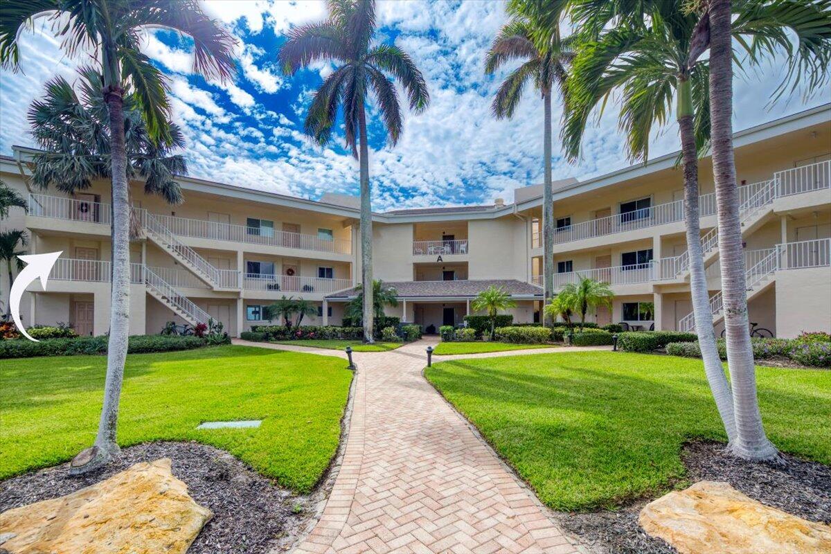 A three-story apartment building with a brick walkway leading to the entrance and palm trees — 2370 NE Ocean Boulevard # A201, Stuart FL 34996, STUART, FL