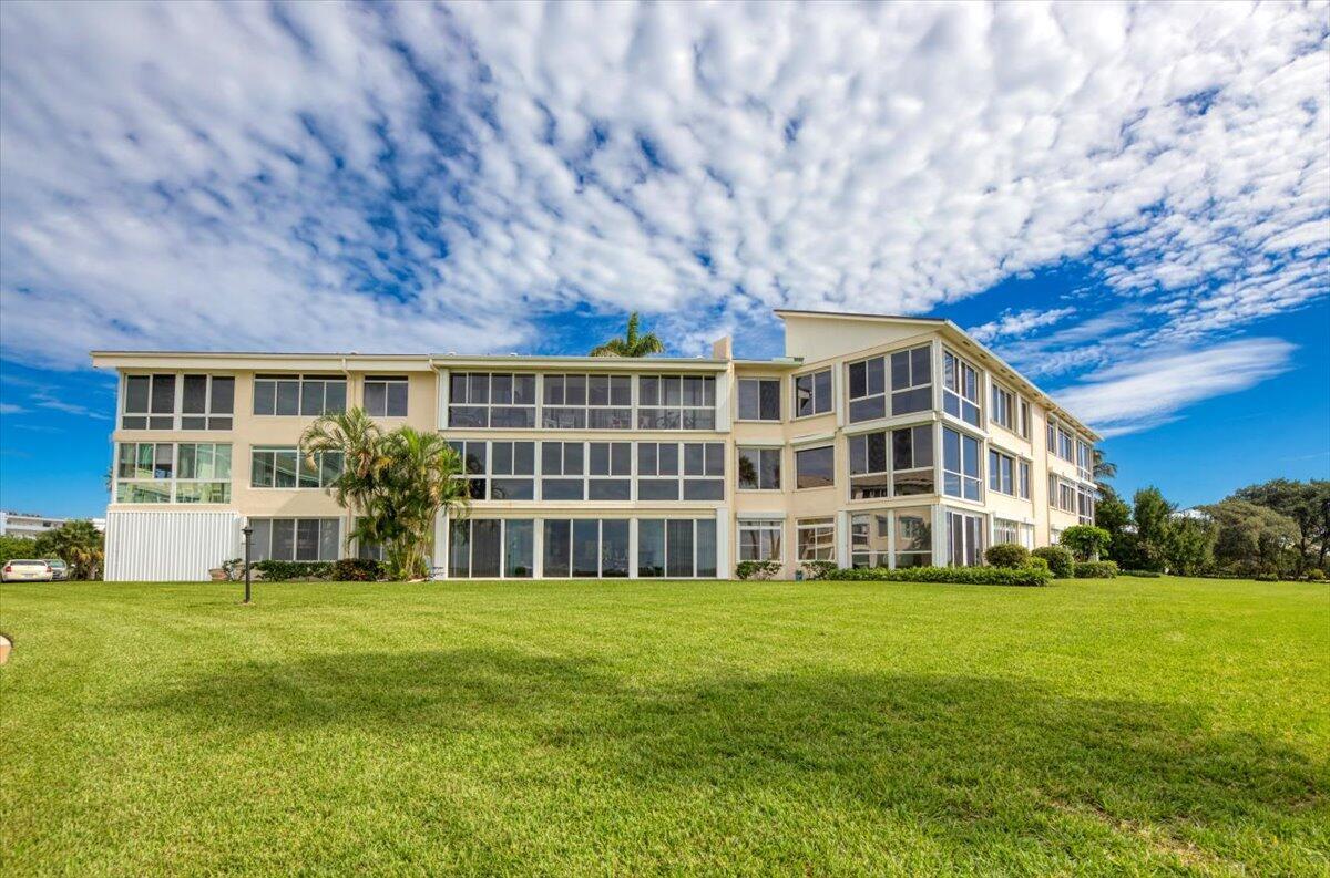 A multi-story apartment building with many windows sits behind a large, green grassy lawn — 2370 NE Ocean Boulevard # A201, Stuart FL 34996, STUART, FL