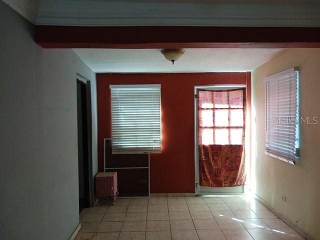 A room with tiled floors, a reddish-orange accent wall, two windows with blinds, and a door — 115 COM SANTA CATALINA 228 UNIT 228, CANOVANAS, PR