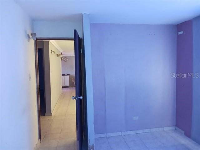 A room with light purple walls and tile flooring leads into a hallway — 115 COM SANTA CATALINA 228 UNIT 228, CANOVANAS, PR
