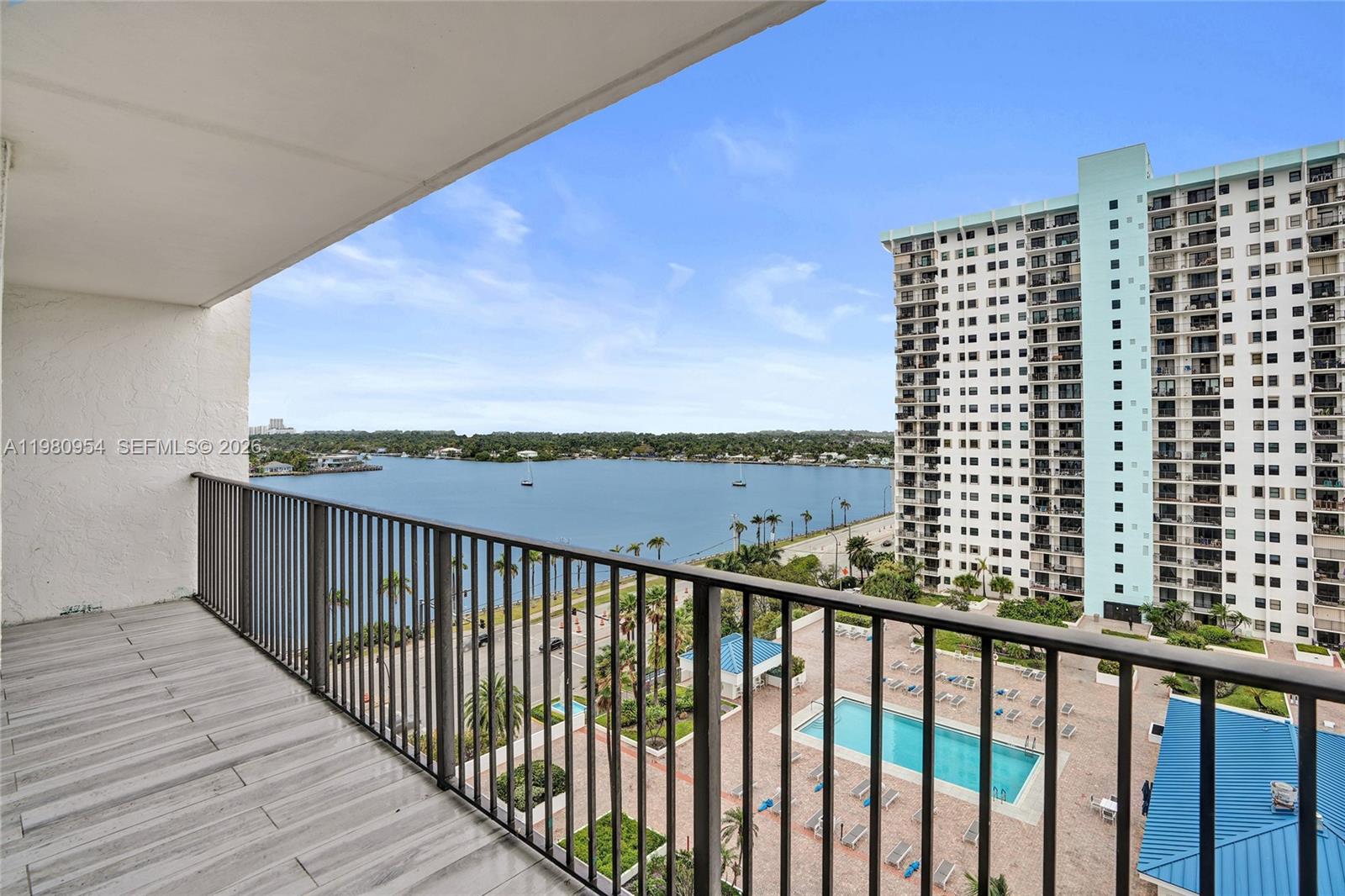 A balcony with metal railings overlooks a swimming pool, a road, and a large bay — 1201 S Ocean Dr # 1407S, Hollywood FL 33019, HOLLYWOOD, FL
