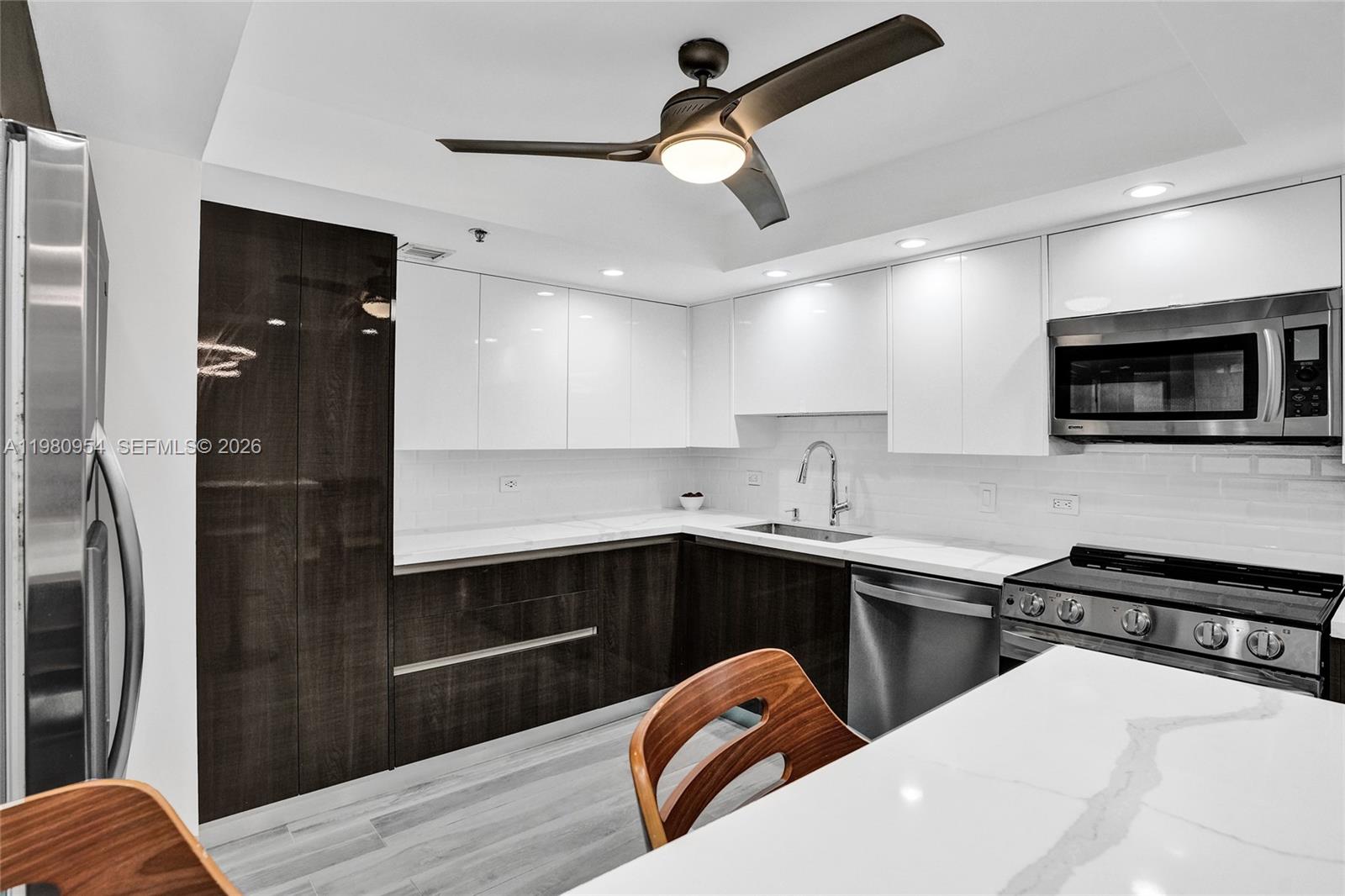 A modern kitchen features white upper cabinets, dark lower cabinets, and a stainless steel stove — 1201 S Ocean Dr # 1407S, Hollywood FL 33019, HOLLYWOOD, FL