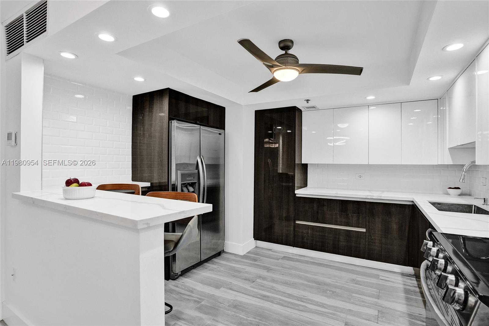 A modern kitchen features dark wood and white cabinetry, stainless steel appliances, and a breakfast bar — 1201 S Ocean Dr # 1407S, Hollywood FL 33019, HOLLYWOOD, FL