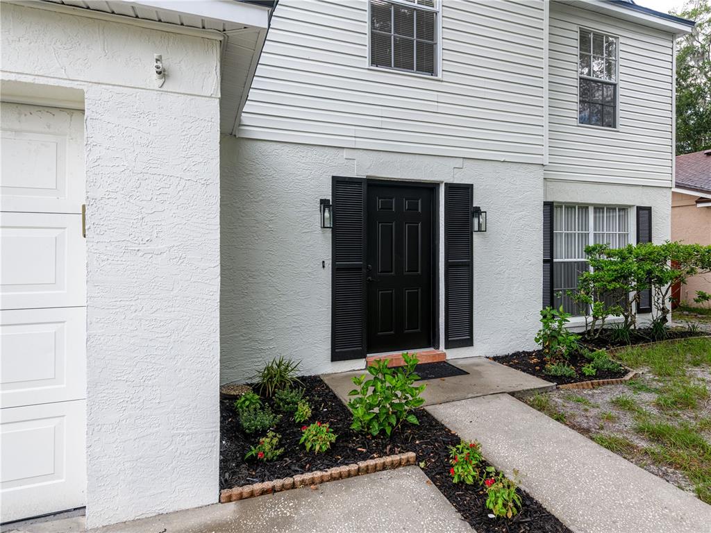 A two-story house exterior features white stucco and siding, a black front door, and shutters — 9703 FOX HOLLOW ROAD, TAMPA, FL