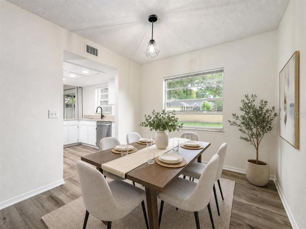 A dining room features a wooden table with six chairs, a light rug, and a plant — 9703 FOX HOLLOW ROAD, TAMPA, FL