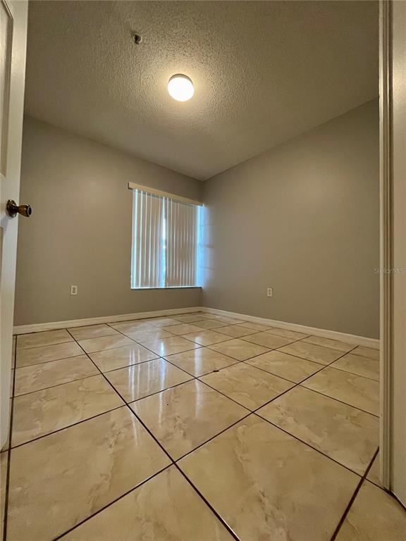 An empty room with light gray walls, a window with vertical blinds, and tiled flooring — 1647 WINDSOR OAK COURT, KISSIMMEE, FL