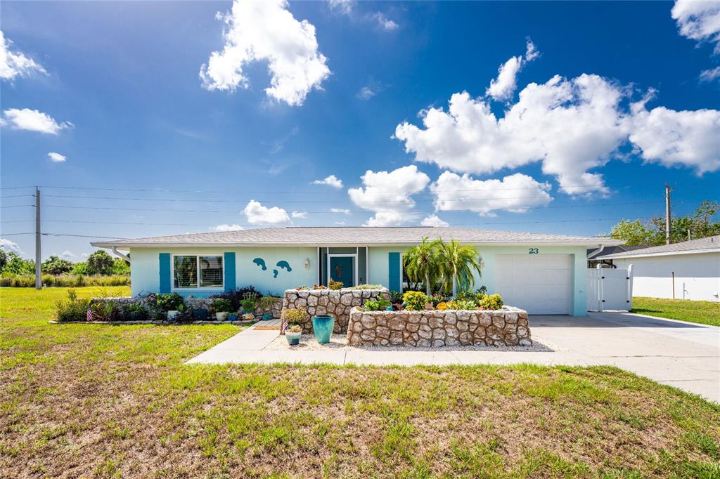 A light green single-story house features a stone planter wall and a one-car garage — 23 ANNAPOLIS LANE, ROTONDA WEST, FL