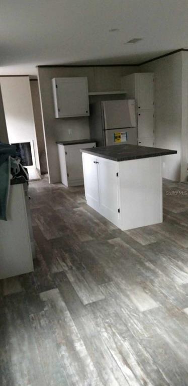 A kitchen features white cabinets, a dark countertop island, and wood-look flooring — 7697 W RADIANCE LANE, HOMOSASSA, FL