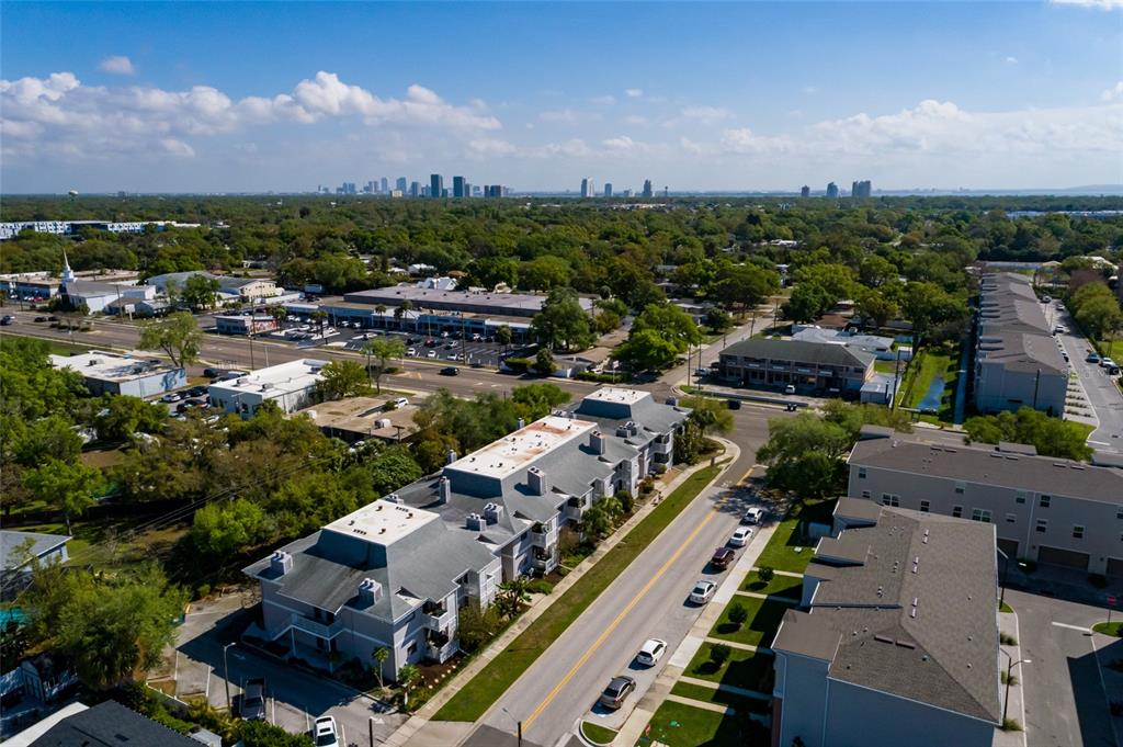 An aerial view shows multi-story apartment buildings, a street with parked cars, and a distant city skyline — 4405 W FAIR OAKS AVENUE UNIT 21, TAMPA, FL
