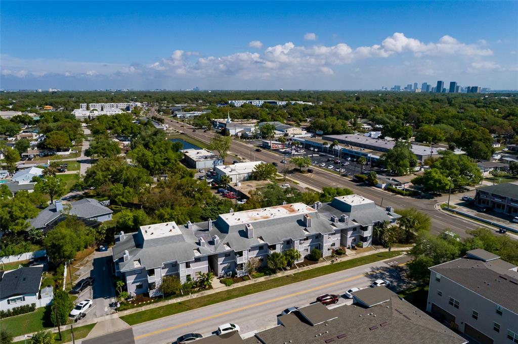 An aerial view shows a multi-story apartment complex situated near a road and commercial buildings — 4405 W FAIR OAKS AVENUE UNIT 21, TAMPA, FL