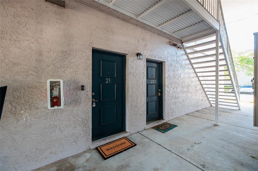 Two dark blue apartment doors with numbers 21 and 23 on a textured exterior wall — 4405 W FAIR OAKS AVENUE UNIT 21, TAMPA, FL