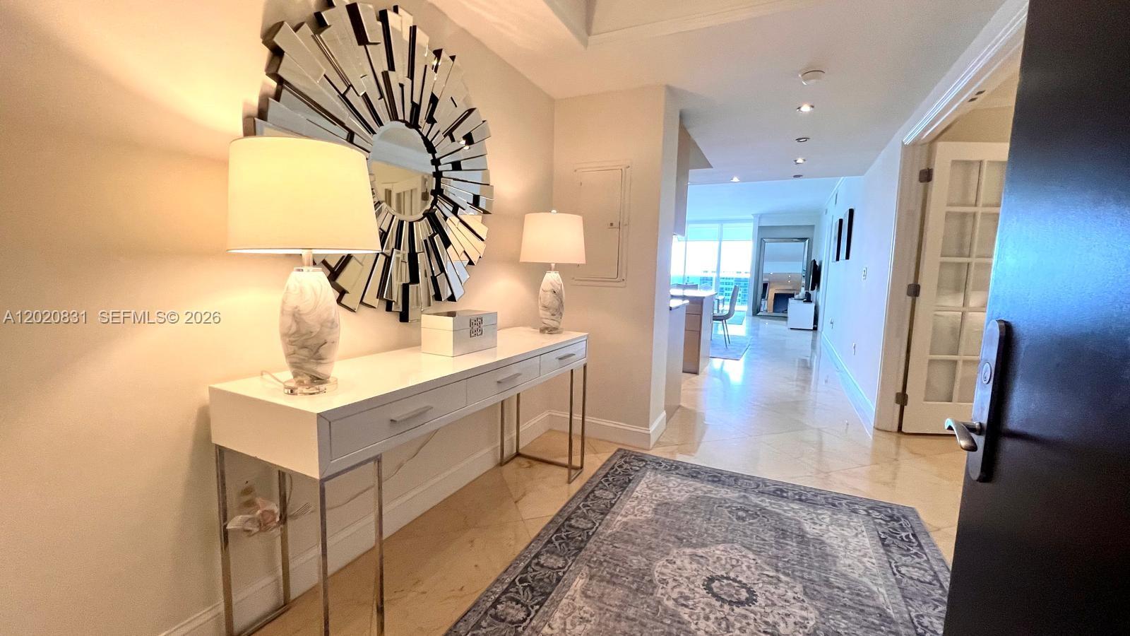 An entryway features a white console table, two lamps, a sunburst mirror, and a rug — 1830 S Ocean Dr # 2204, Hallandale Beach FL 33009, HALLANDALE BEACH, FL