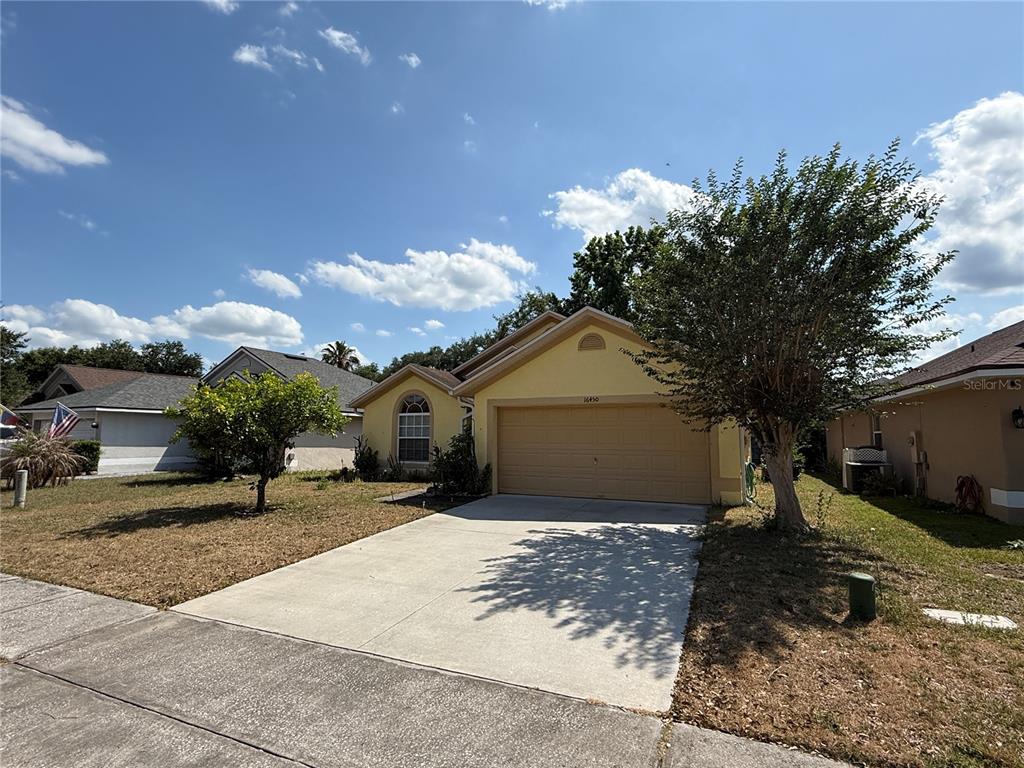 A yellow single-story house with a two-car garage and a concrete driveway — 16450 GOLDEN EAGLE BOULEVARD, CLERMONT, FL