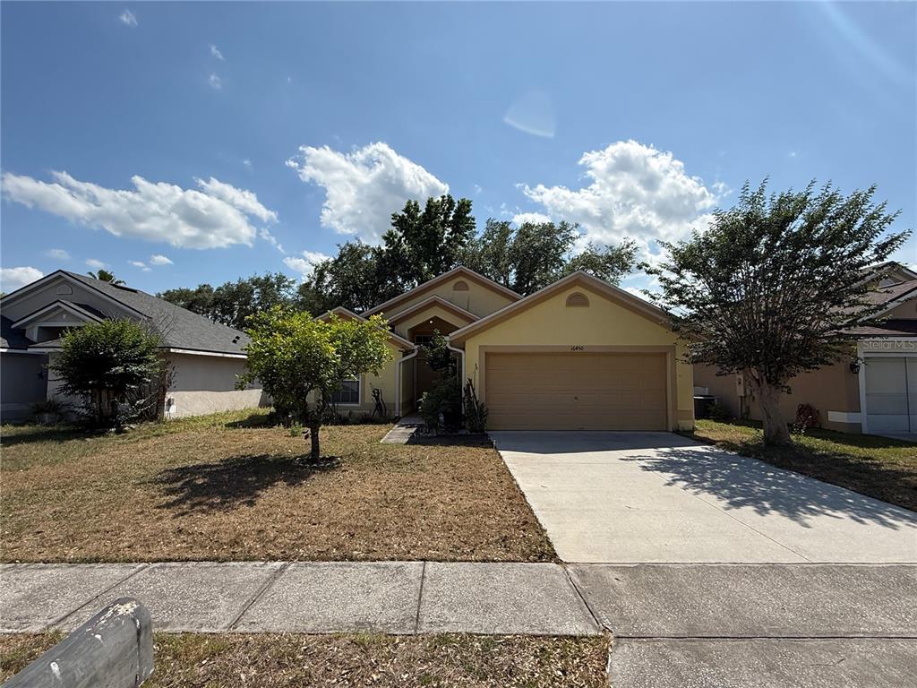 A single-story yellow house with a two-car garage and a concrete driveway — 16450 GOLDEN EAGLE BOULEVARD, CLERMONT, FL