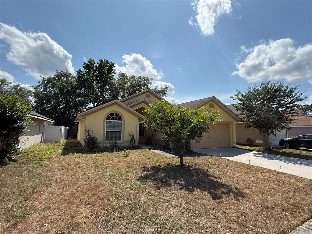 A yellow single-story house with a two-car garage and a front yard — 16450 GOLDEN EAGLE BOULEVARD, CLERMONT, FL