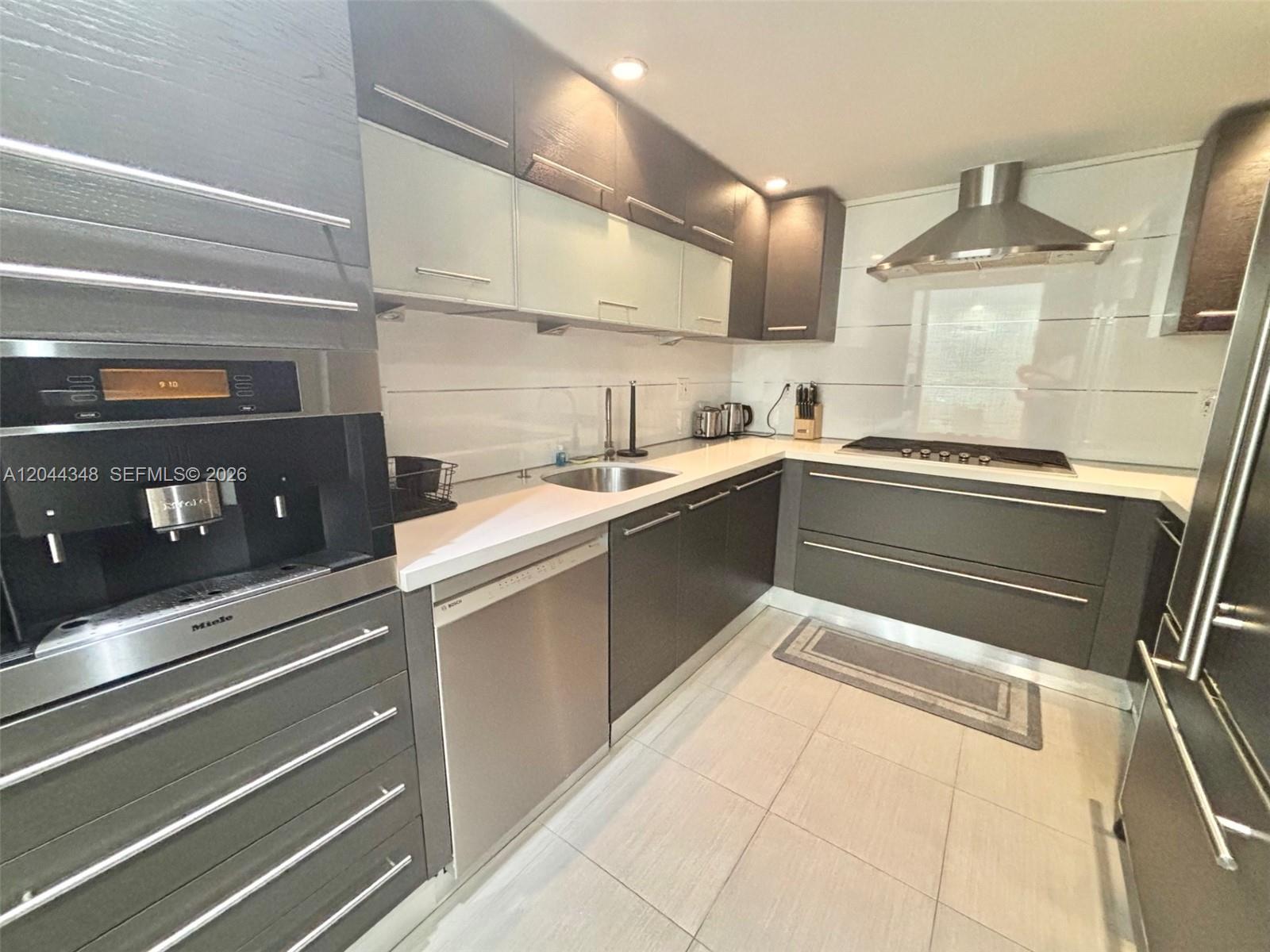 A modern kitchen features dark grey cabinetry, stainless steel appliances, and white countertops — 2030 S Ocean Dr # 423, Hallandale Beach FL 33009, HALLANDALE BEACH, FL