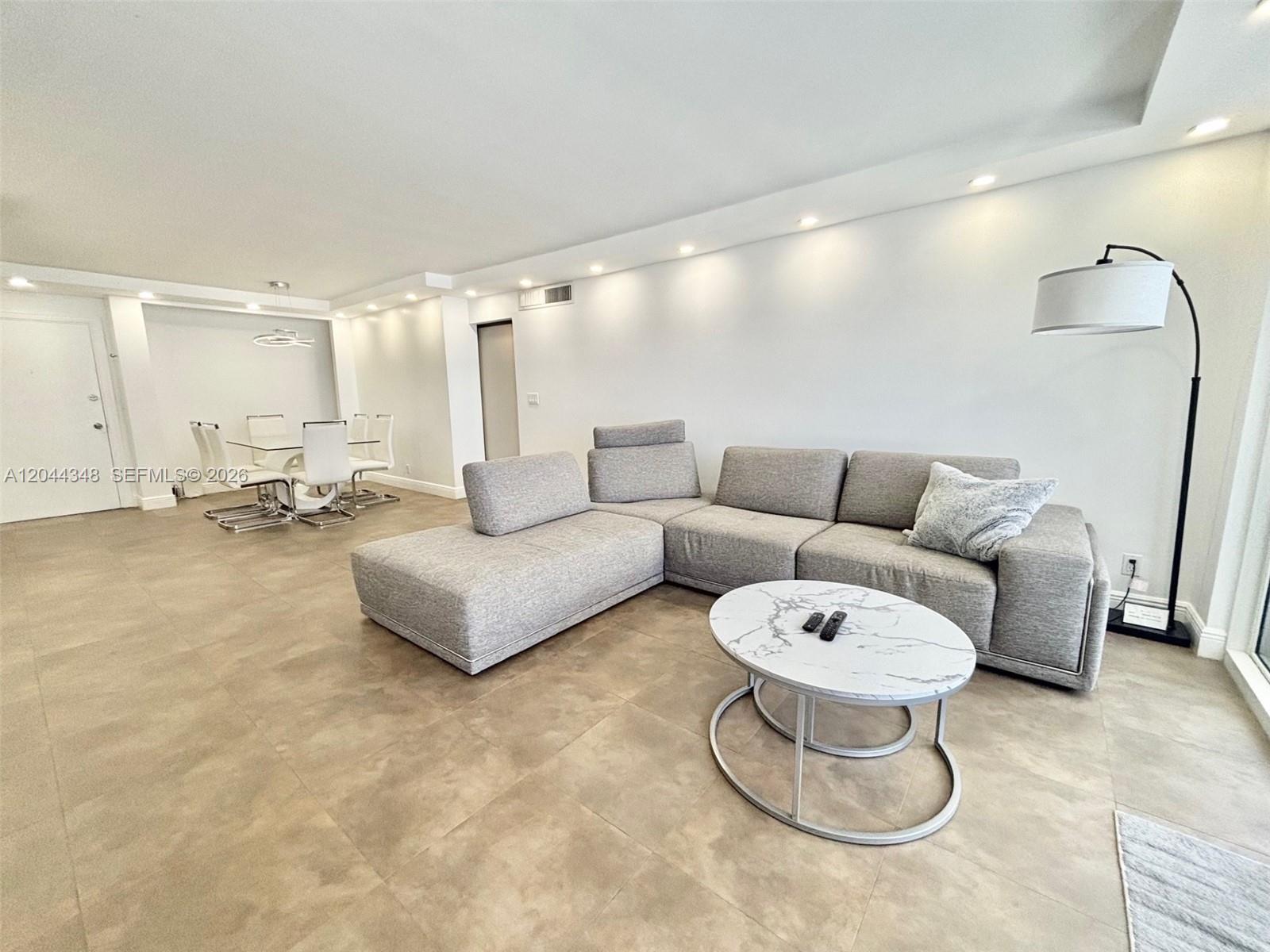 A modern living room features a gray sectional sofa, marble coffee table, and tile flooring — 2030 S Ocean Dr # 423, Hallandale Beach FL 33009, HALLANDALE BEACH, FL